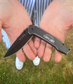 Stonewash frame lock folder knife in hands and engraved with logo