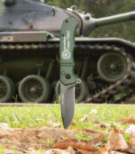 Green tactical knife in front of tank