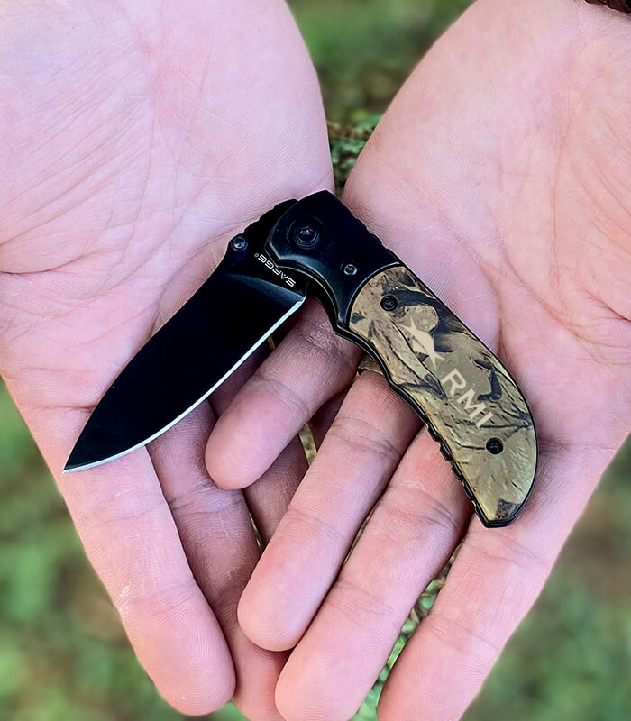 Camo knife in hands engraved with logo
