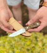 fixed blade bird knife being held with it's light tan sheath